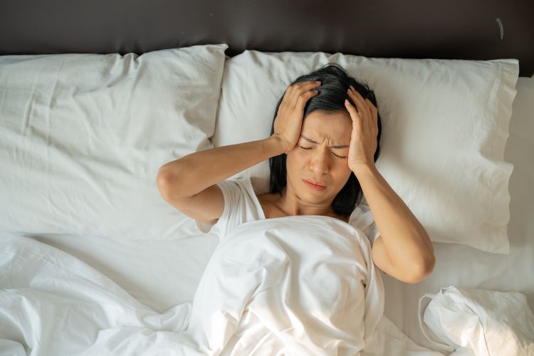 Mujer tumbada en la cama sufriendo dolor de cabeza debido al insomnio, falta de sueño