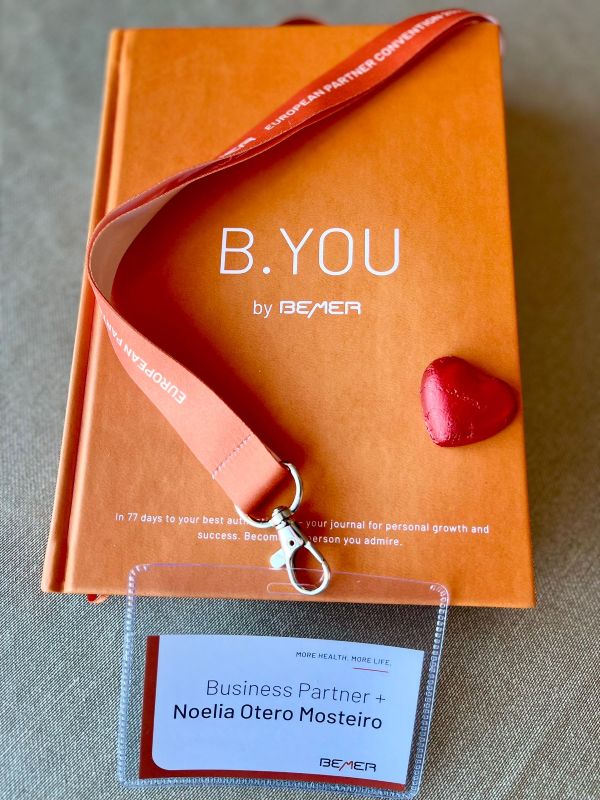 Libro B.YOU de BEMER en color naranja con lanyard y tarjeta identificativa de Noelia Otero